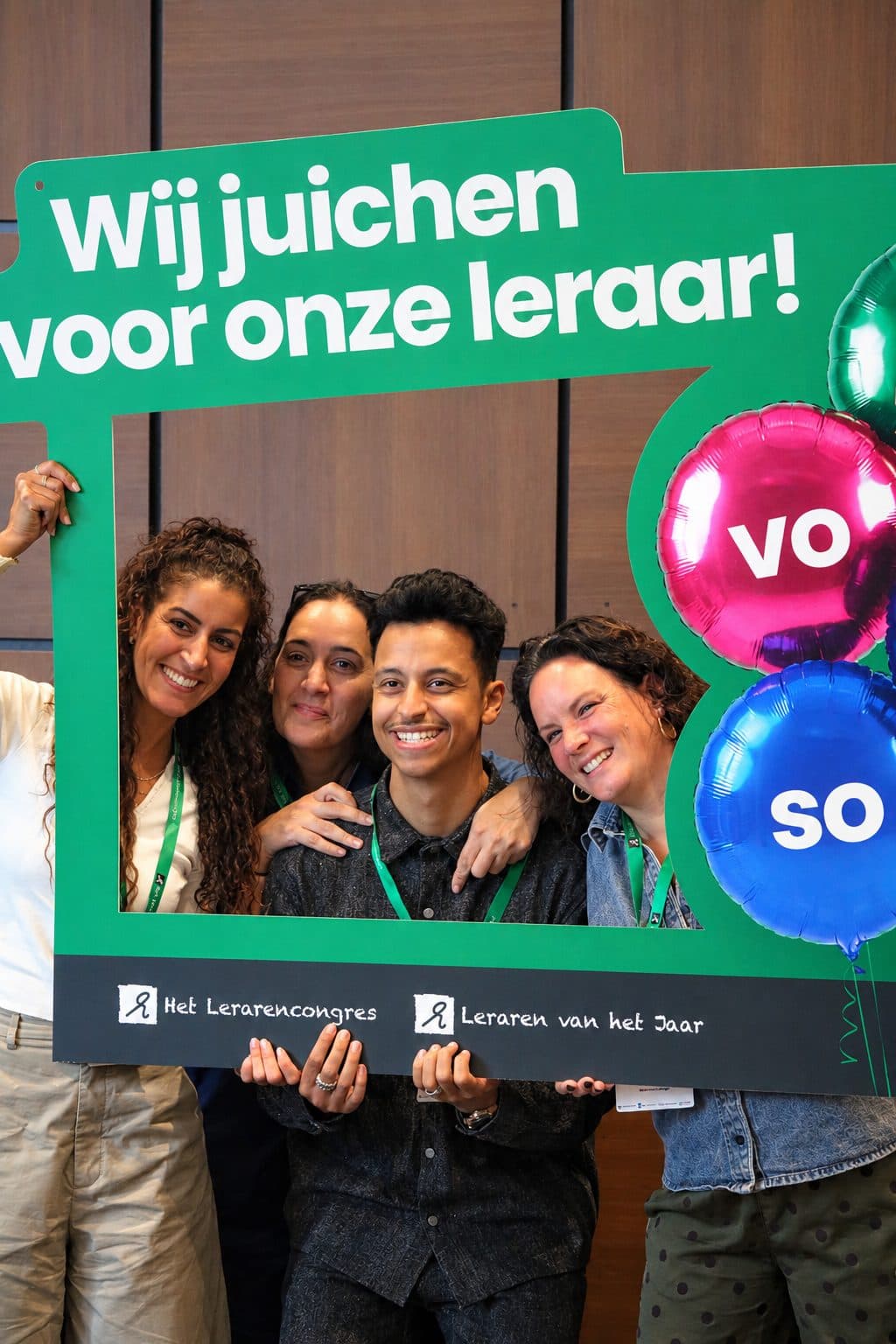 Bilal en collega's poseren met een fotolijst met de tekst 'Wij juichen voor onze leraar!'