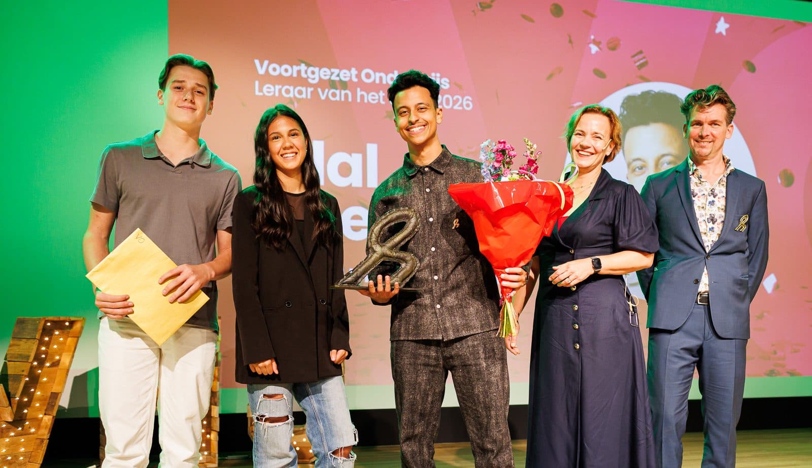 Groepsfoto op het podium met Bilal, bloemen en de trofee