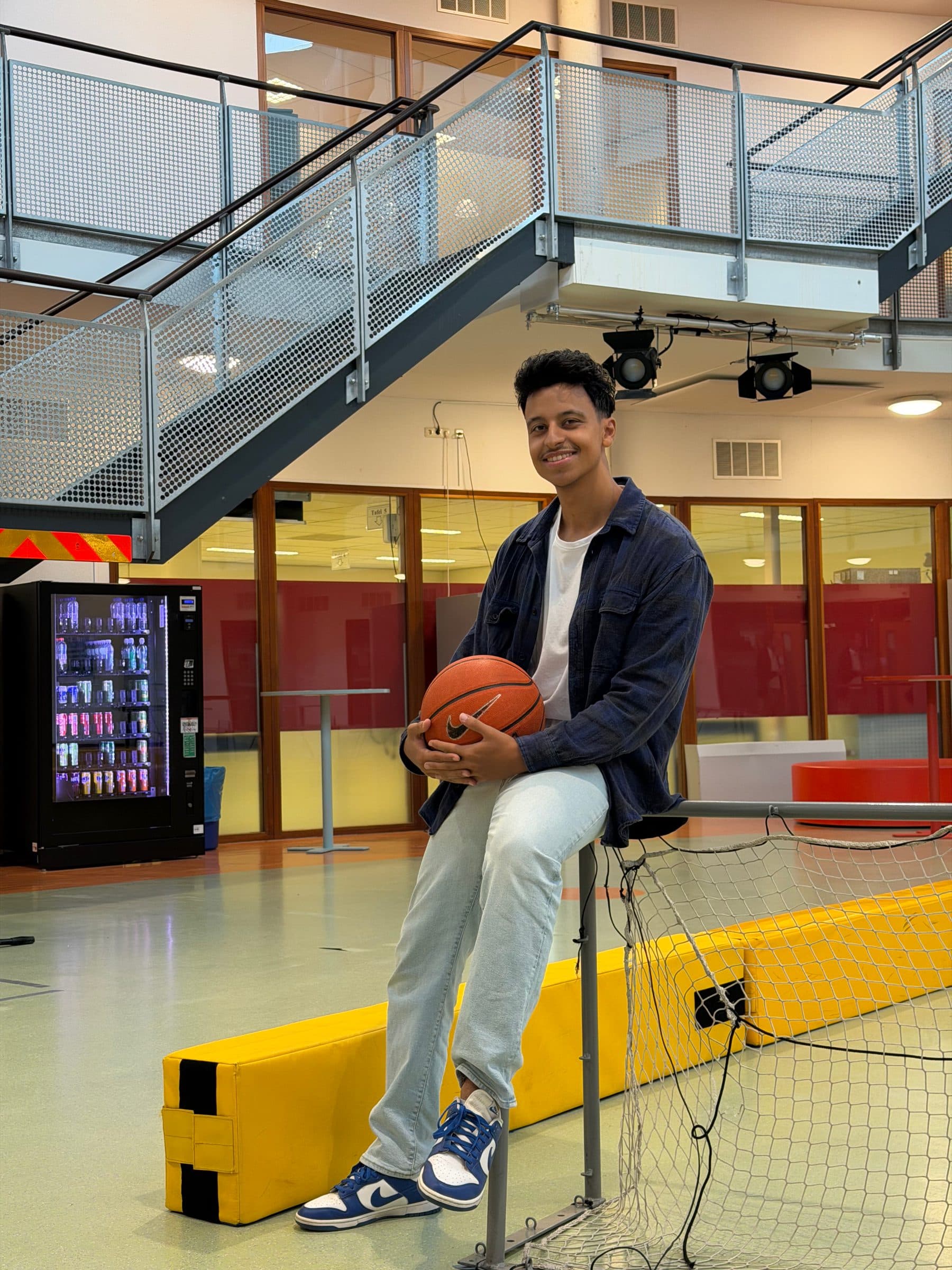 Bilal geeft twee leerlingen een high five in het atrium van school